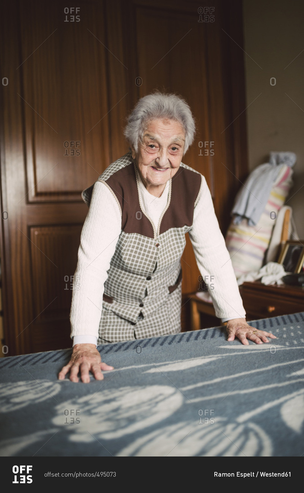 Senior woman putting fresh sheets on a bed