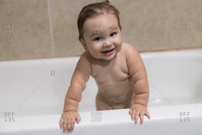 Baby boy standing in bathtub