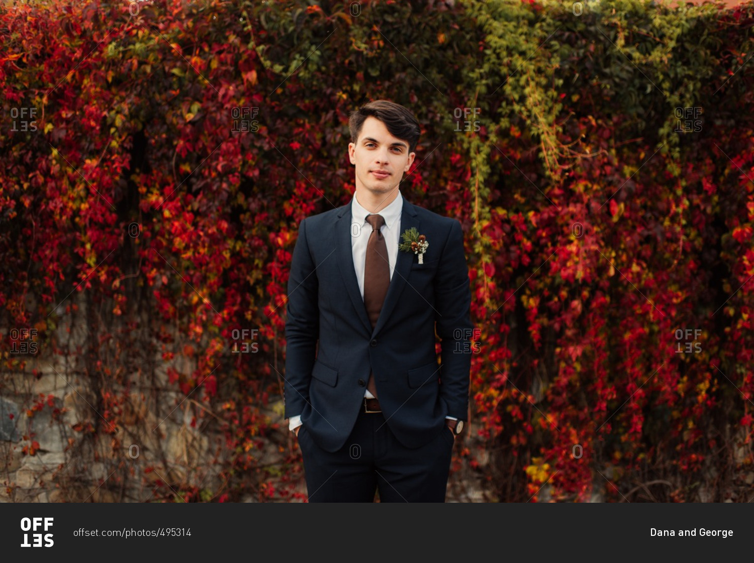Groom standing by colorful fall vines
