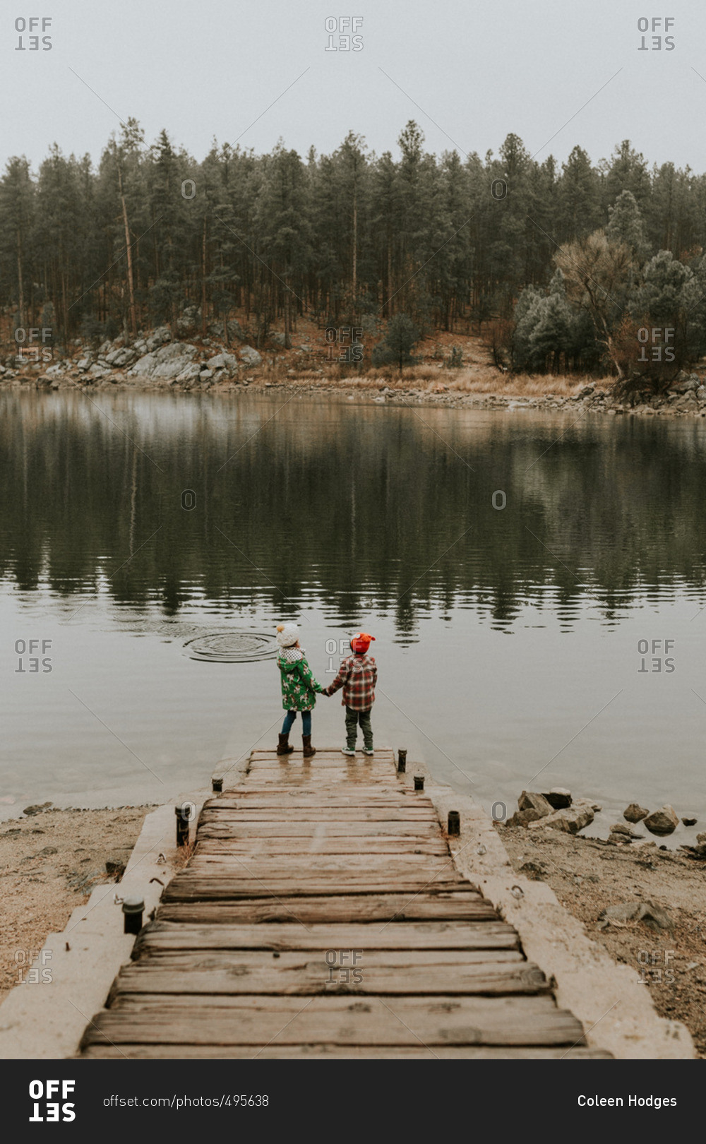 Kids holding hands by lake in cold weather