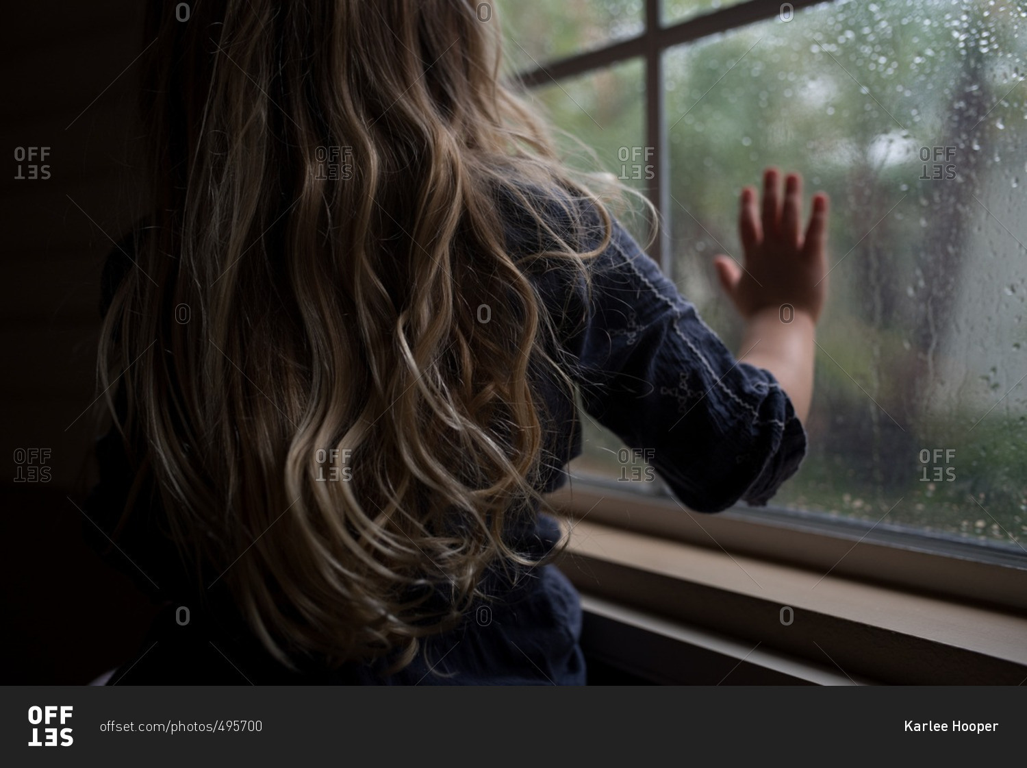 Girl with hand on rainy window