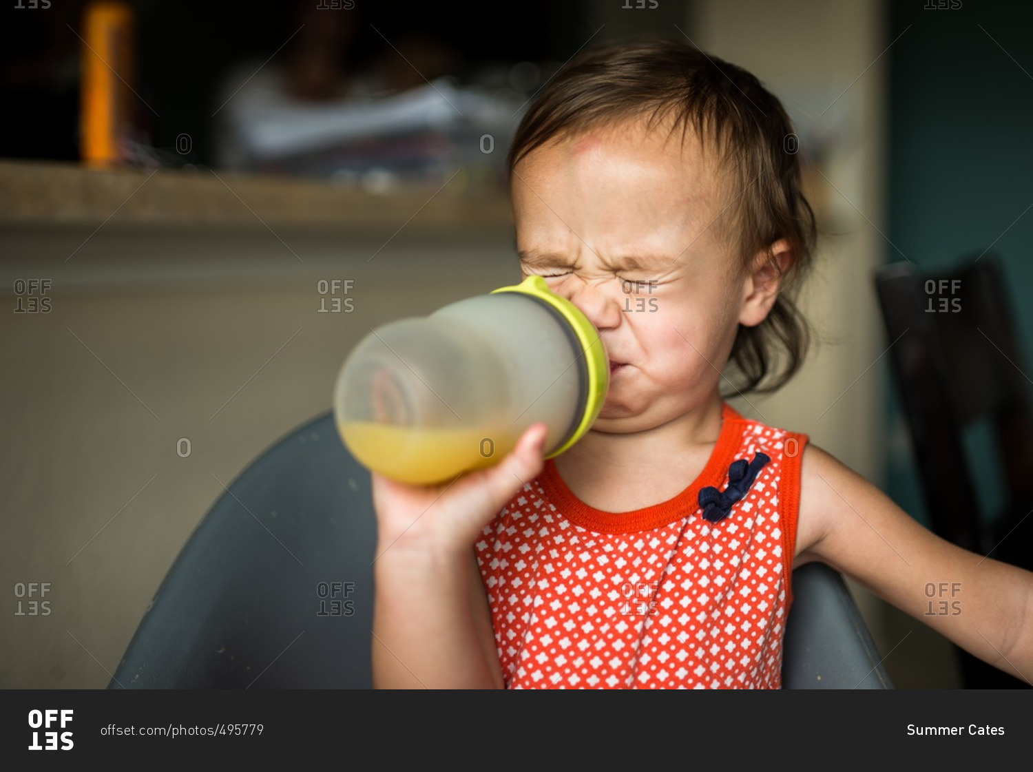 Toddler girl making sour face while sipping on a juice cup