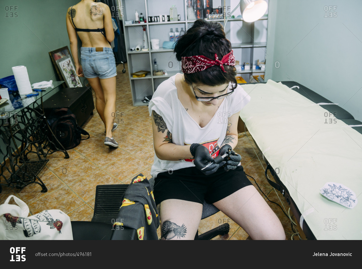 Stylish hipster tattoo artist tattooing a woman in her studio