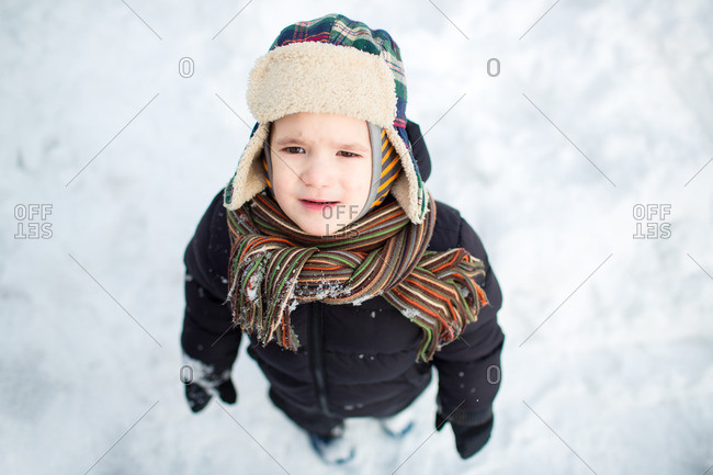 Top view of an unhappy little child in warm clothes looking up and frowning