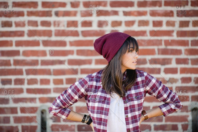 A hip woman looking off by brick wall