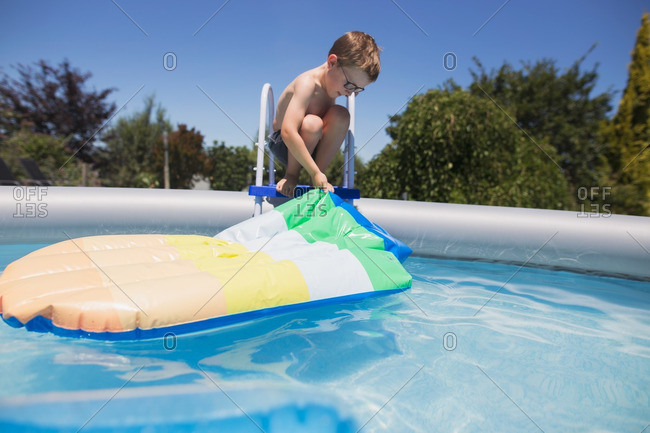 Boy in glasses pulling float out of pool