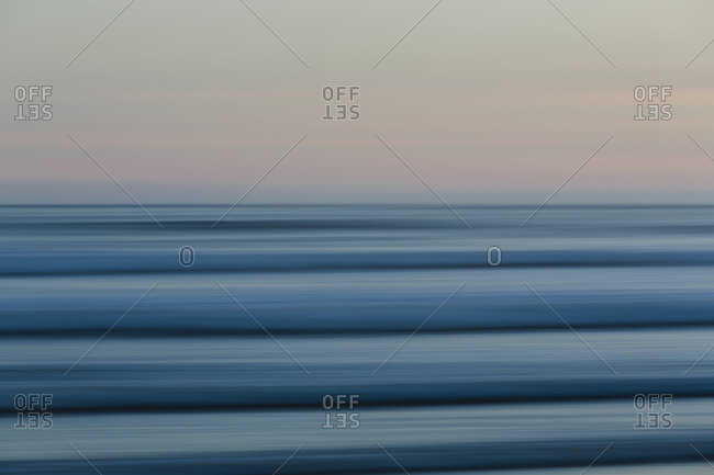Ocean waves and the view to the horizon over the sea at dusk from the beach.
