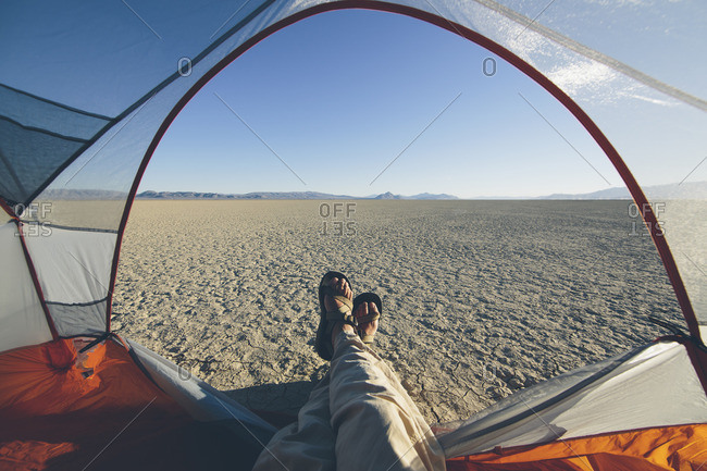 Man reclining in camping tent, expansive desert and playa in distance, Black Rock Desert, Nevada
