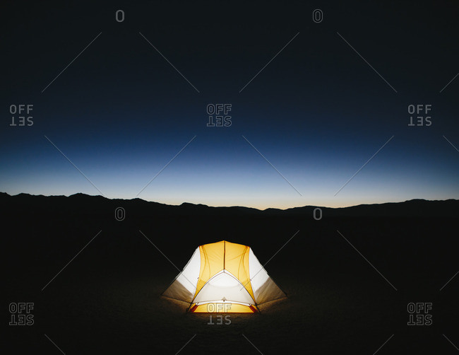 Illuminated camping tent in vast desert at dusk, Black Rock Desert, Nevada