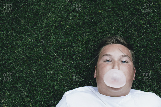 Portrait of teenage boy blowing bubble gum bubble