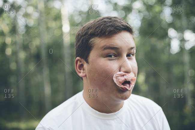 Portrait of teenage boy blowing bubble gum bubble