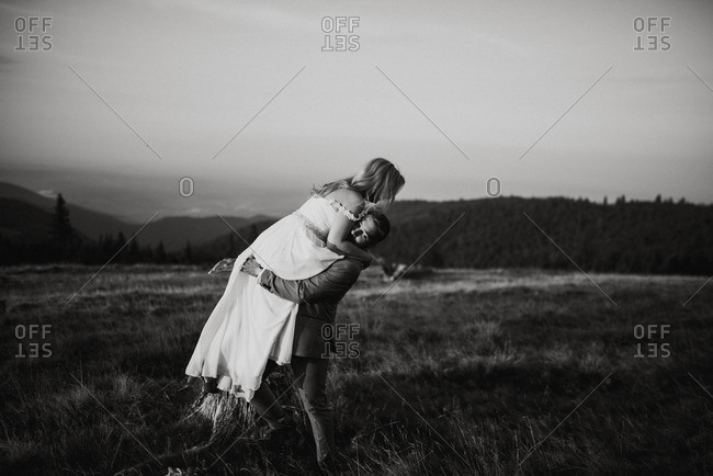 Groom lifting bride in the air in a field