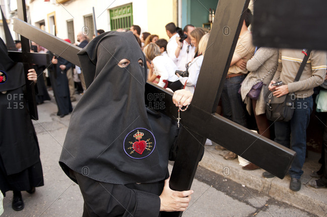 Person carrying a cross during an Easter procession in Seville, Spain