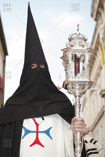 Person in a hooded robe holding a sceptre during an Easter procession in Seville, Spain