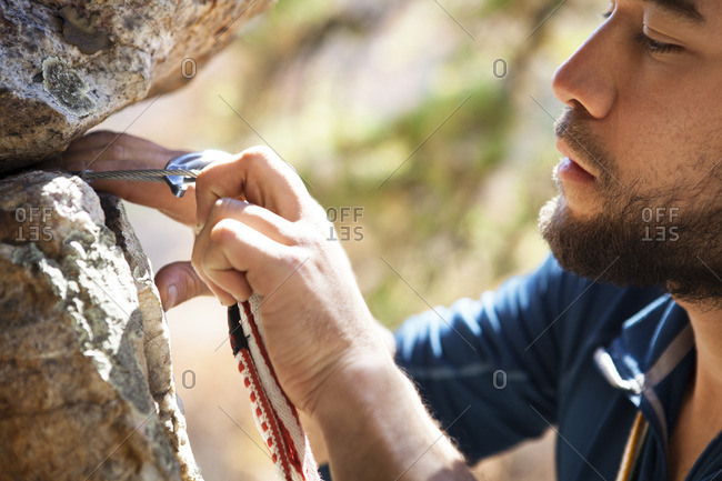 Cropped image of climber attaching carabiner on rocks