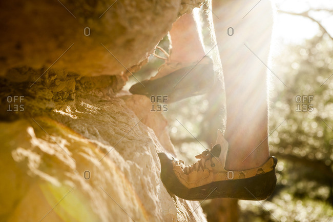 Low section of man rock climbing on sunny day