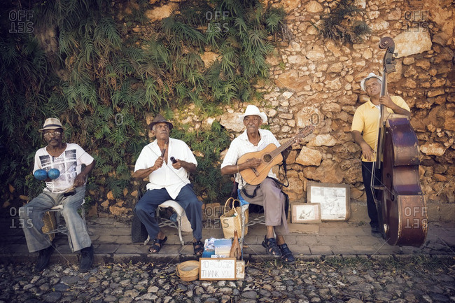 Street musicians playing musical instruments against stone wall
