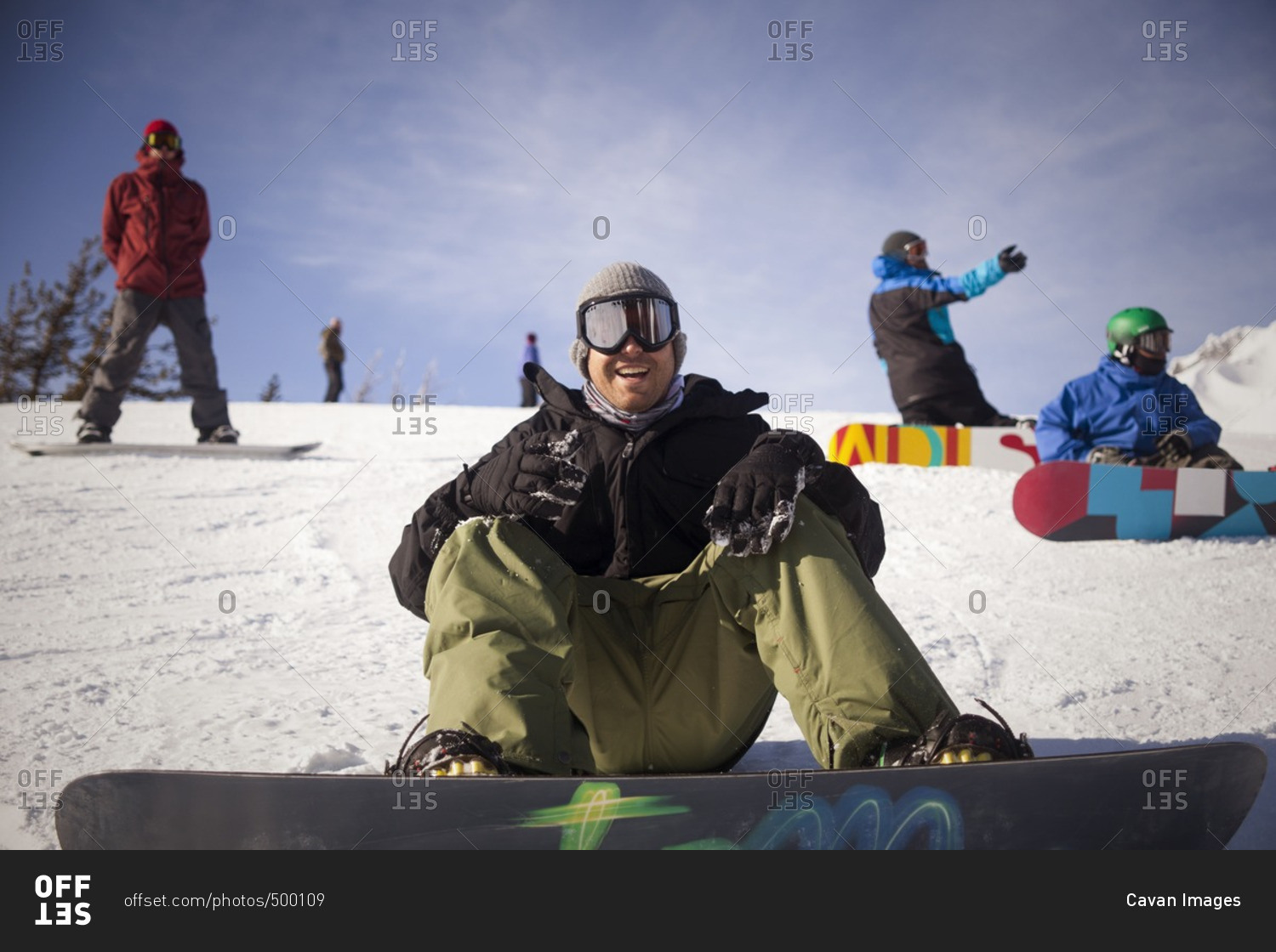 Cheerful friends with snowboarding on snowy field against sky