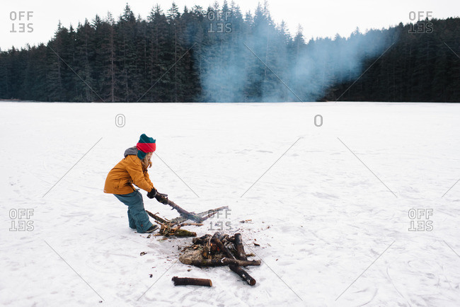 Child making fire in snowy field