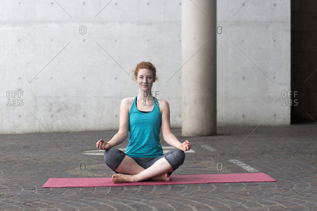 Young woman doing yoga on yoga mat in atmospheric yoga studio stock photo -  OFFSET