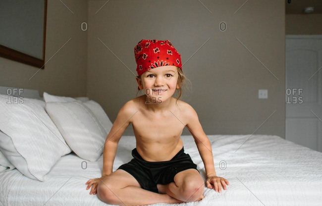 Happy boy wearing red bandana on a bed