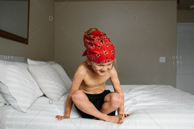 Happy boy with a red bandana sitting on a bed