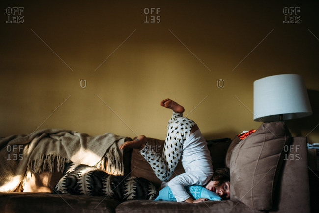 Girl playing on a couch with her legs up in the air