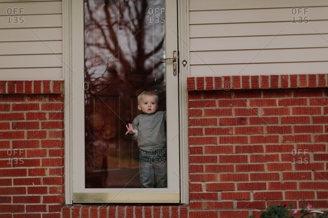 Toddler Boy Looking Out A Glass Door Stock Photo Offset
