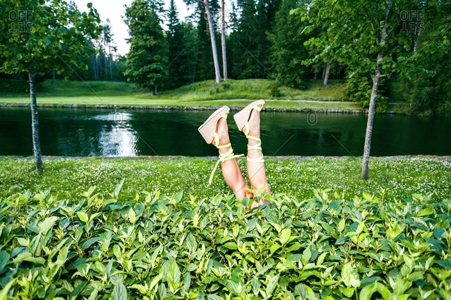 Woman\'s feet wearing yellow strappy sandals up in the air by a lake