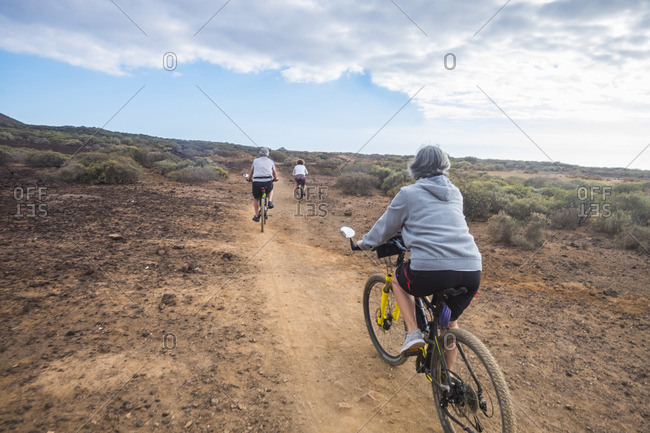 Three people pedaling mountain bikes through desert