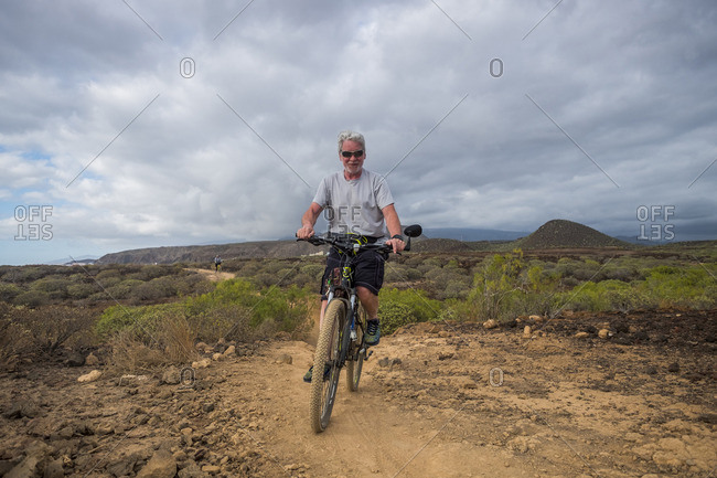 Senior man riding mountain bike in desert
