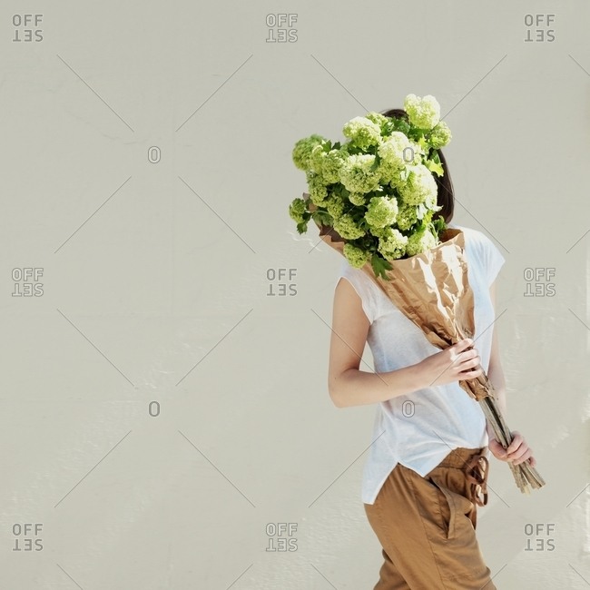 Woman with bouquet of flowers covering her face