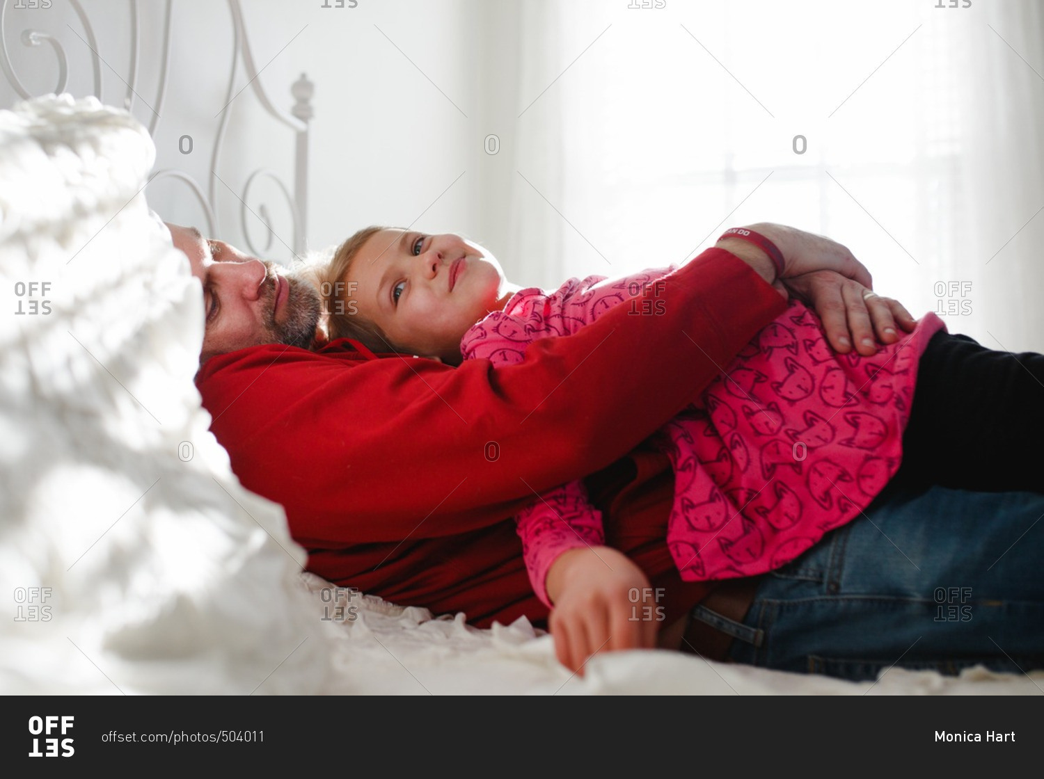 Dad and daughter cuddling on a bed stock photo OFFSET