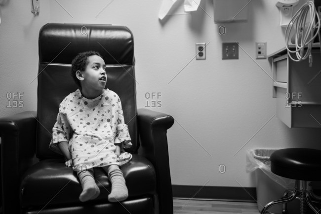 Girl in hospital gown waiting in char