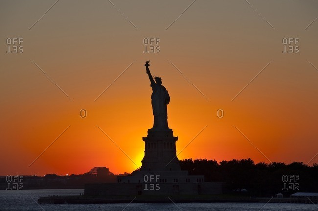 Silhouetted Statue of Liberty photographed against the setting sun Liberty Island, New York, USA