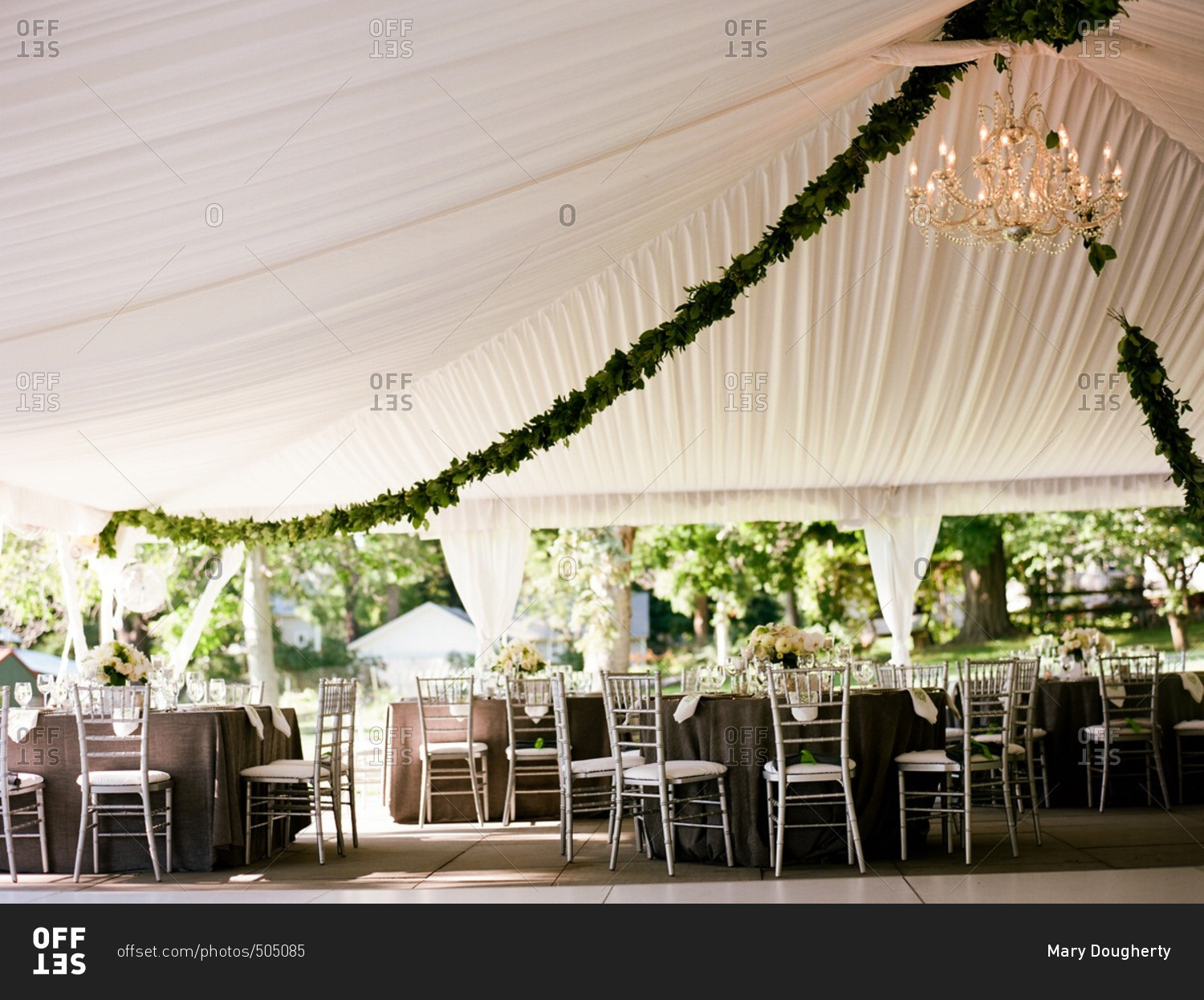 Tables set under a billowy white open-air canopy for a special event