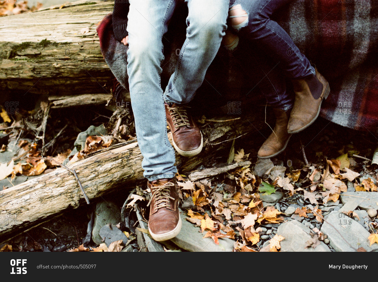 Couple curled up on a flannel blanket on a fallen log