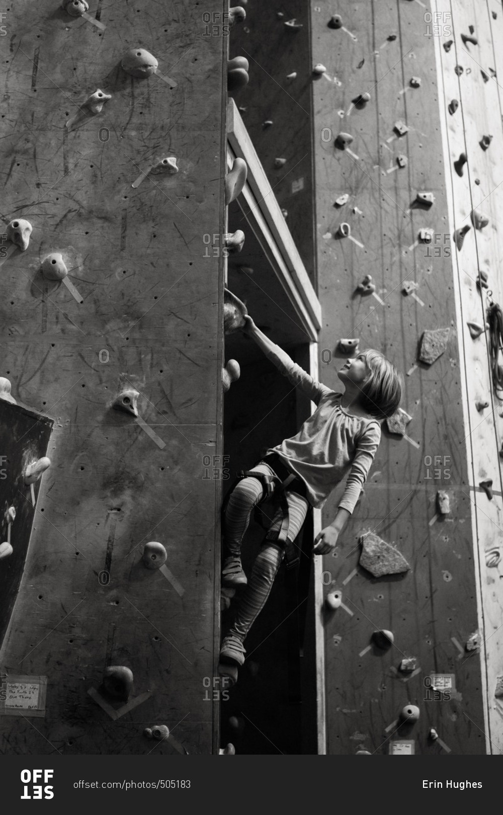 Young girl climbing up a rock wall in black and white
