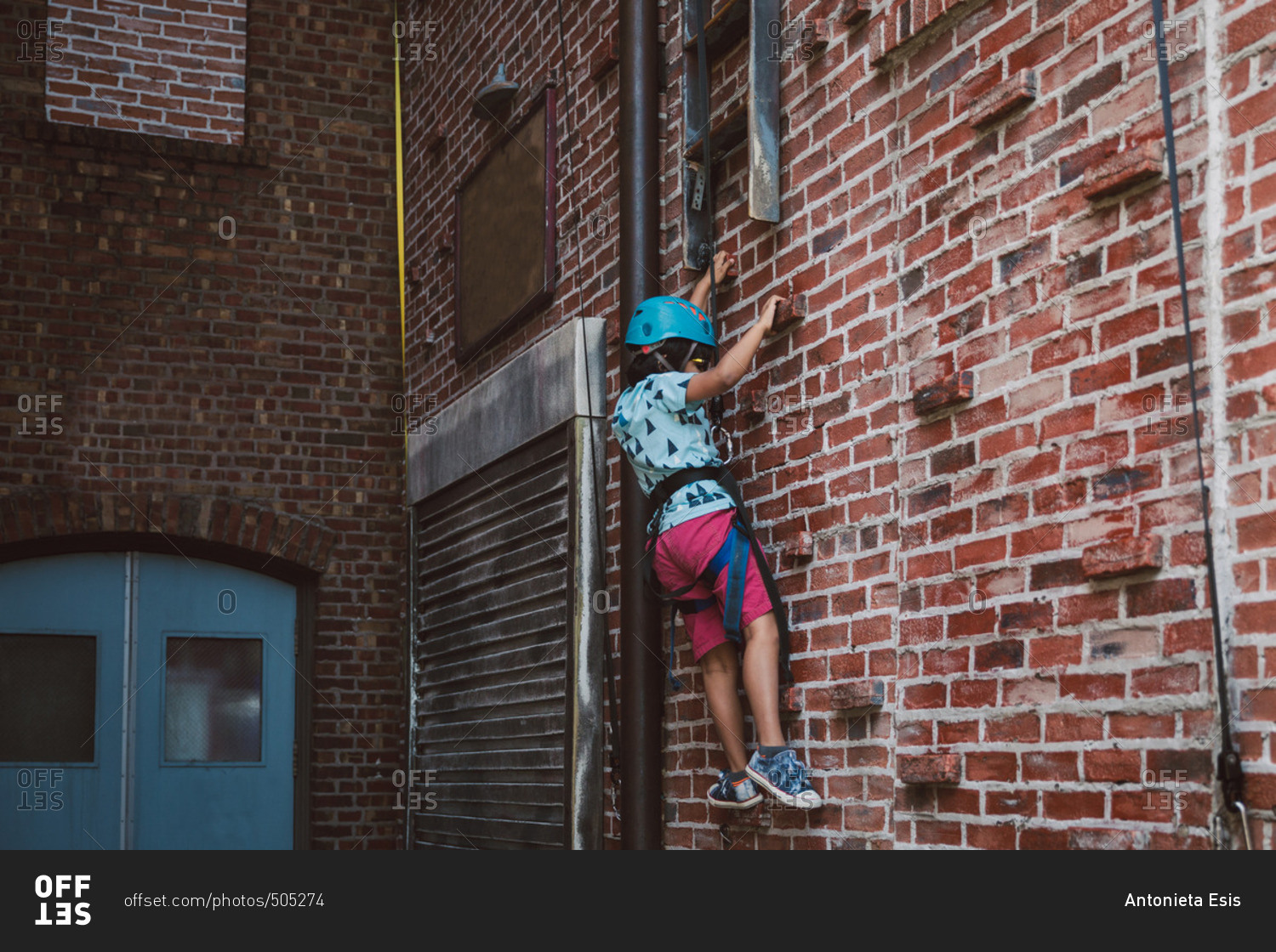 Young boy climbing a brick wall stock photo OFFSET