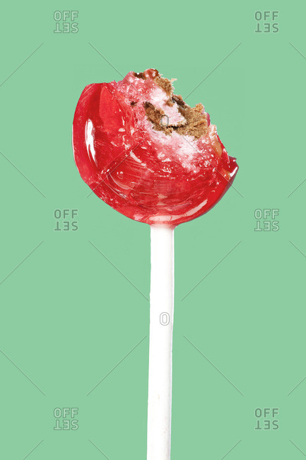 Close up of partially eaten lollipop in front of teal background