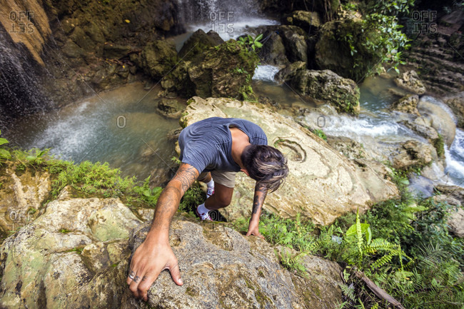 Man rock climbing near waterfalls and pools on java
