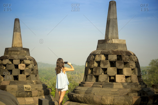 Woman taking pictures of stupas on Borobudur temple in Indonesia