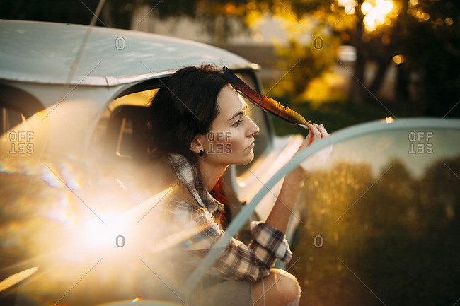 Woman is sitting with feather in the car and peering into distance