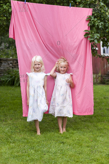 two blonde girls standing in front of laundry in back yard