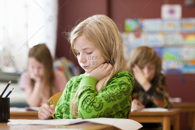 Schoolgirl writing in notebook at classroom