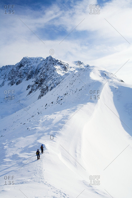 Two Snowshoers Ascend A Ridge Above Eagle River In Chugach State Park. Winter In South-central Alaska.