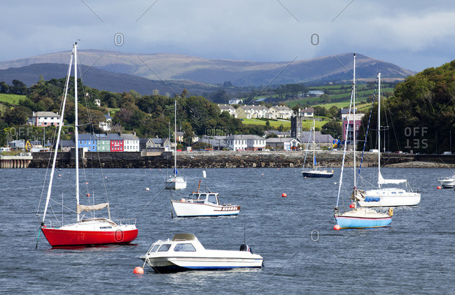 Boats moored in the harbor with storm clouds and mountains in the distance; Bantry, County Cork, Ireland