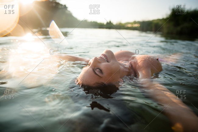 Nude woman lying on water in the lake, summer day
