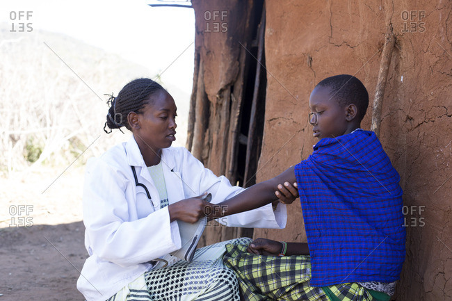 Doctor examines a woman's arm in Maasai village, Africa stock ...