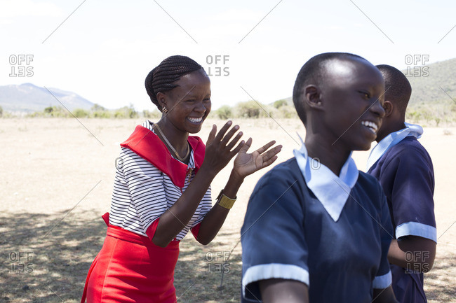 Teacher playing with school children outdoors, Kenya
